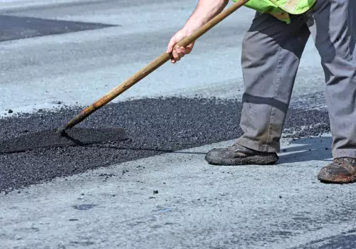 Man fixing the road with asphalt binder mixture during asphalt repair in Bloomington IL